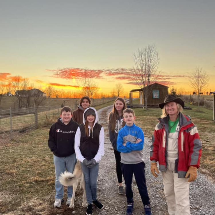  group of 4H livestock club members on a farm in front of a sunset
